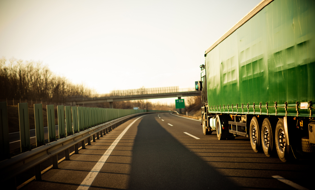 Green truck on the highway, representing CloudConnect’s packing optimization solution for sustainable and efficient shipping.