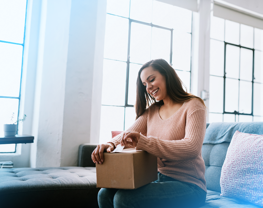 Woman smiling while opening a package, representing the excitement of a seamless customer journey with NetSuite and HubSpot integration.