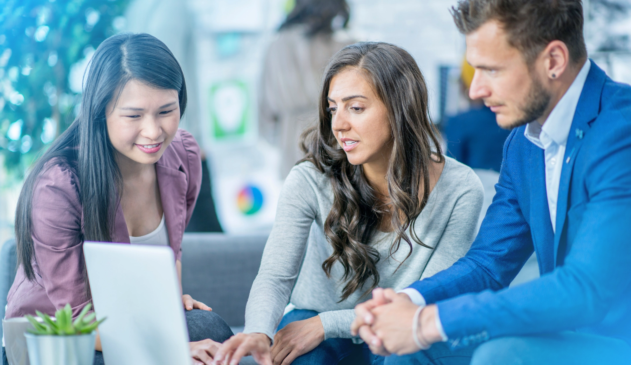 Colleagues collaborating over a laptop, highlighting the teamwork and creative spirit that fuels professional growth in NetSuite careers at CloudConnect.